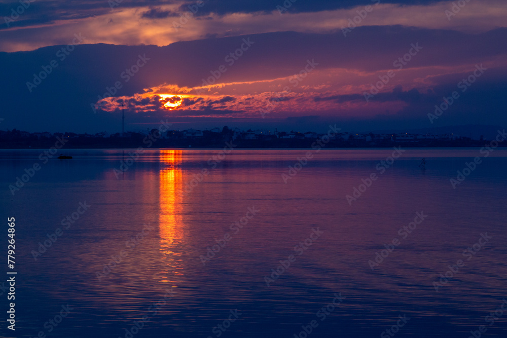 Naklejka premium Sunset over the sea with dramatic sky and reflection in the water. Beautiful sunset on the lake in the evening. Nature composition.