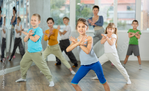 Active preteen girl practicing sport dances with other children and teacher during dancing classes