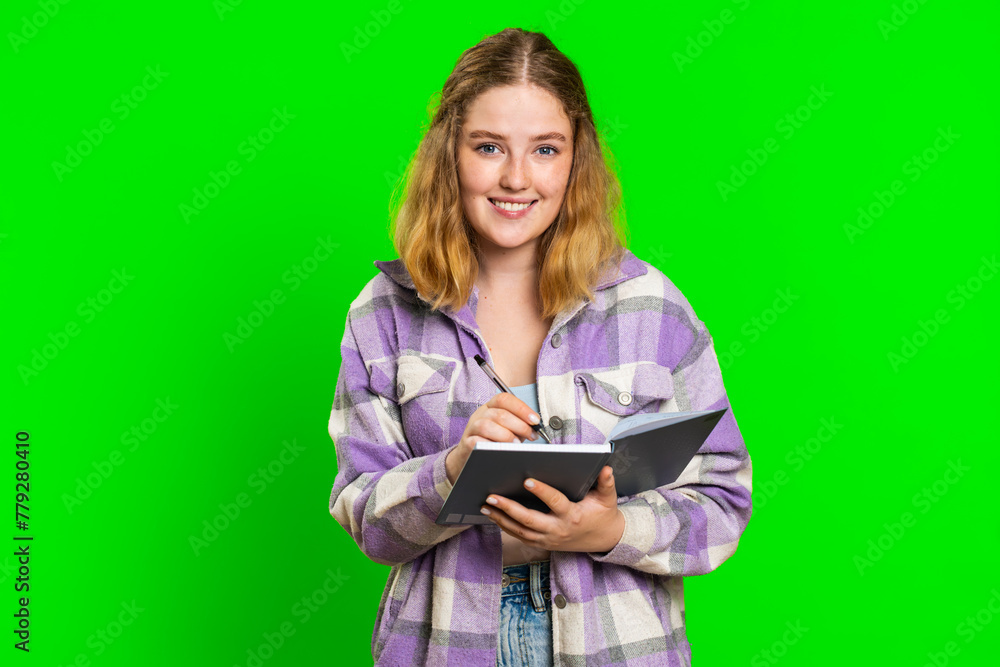 Thoughtful journalist young woman making notes, writing down thoughts with pen into notepad notebook diary, to do list, good idea. Pretty redhead student girl isolated on green chroma key background Thoughtful journalist young woman making notes, writing down thoughts with pen into notepad notebook diary, to do list, good idea. Pretty redhead student girl isolated on green chroma key background