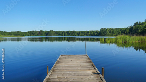 A peaceful lakeside dock extending into calm waters, reflecting the clear sky.