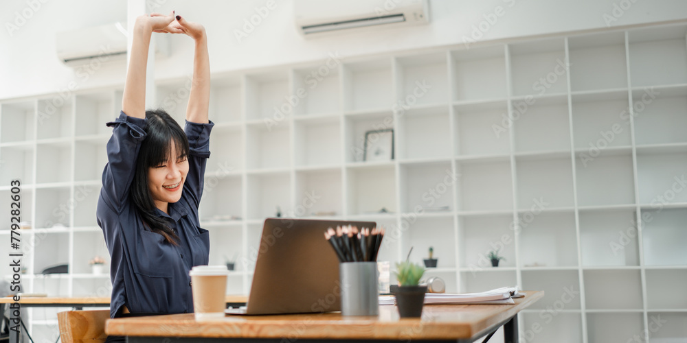 Young businesswoman enjoying a stretching break at her desk to rejuvenate during a busy workday at the office. Young businesswoman enjoying a stretching break at her desk to rejuvenate during a busy workday at the office.