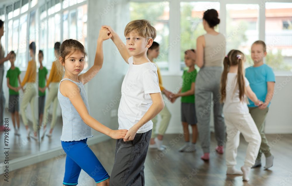 Fototapeta premium Preteen children learn to dance tango under guidance of a teacher in the ballroom