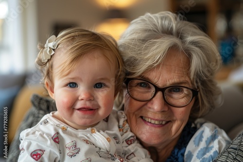 Tender moment between a smiling toddler and her bespectacled grandmother indoors