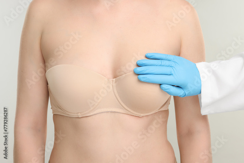 Mammologist checking woman's breast on light grey background, closeup © New Africa