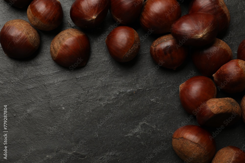 Roasted edible sweet chestnuts on grey textured table, flat lay. Space for text Roasted edible sweet chestnuts on grey textured table, flat lay. Space for text