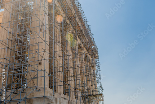 Scaffolding enveloping an ancient monument during restoration against a blue sky