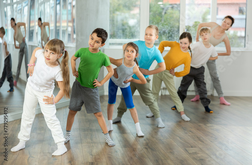 Group of children boys and girls with coach warming up before dance class in studio