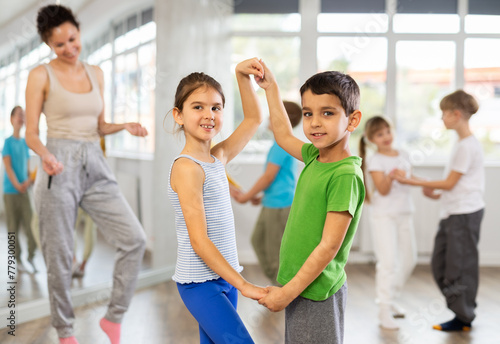 Group of schoolchildren training movements of slow foxtrot in dance studio with female tutor