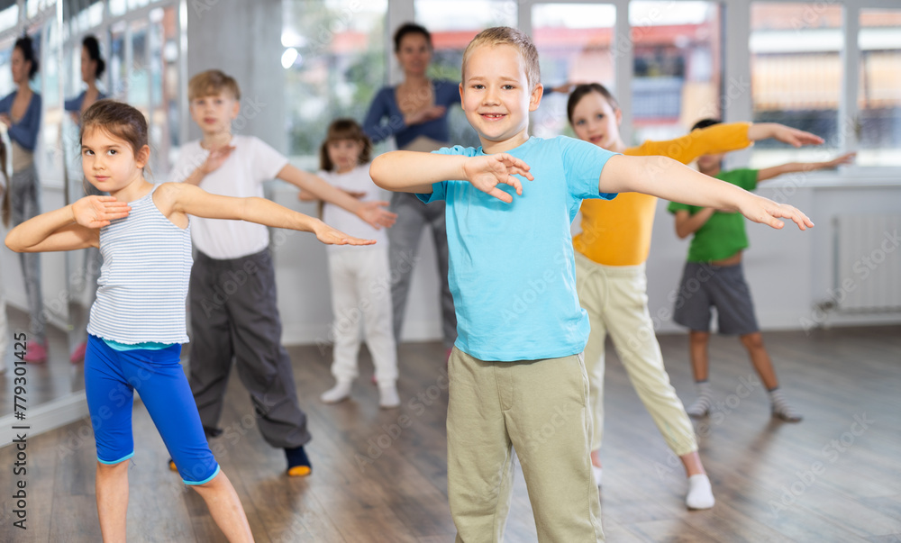 Fototapeta premium Children studying modern style dances with female teacher in dance class indoors
