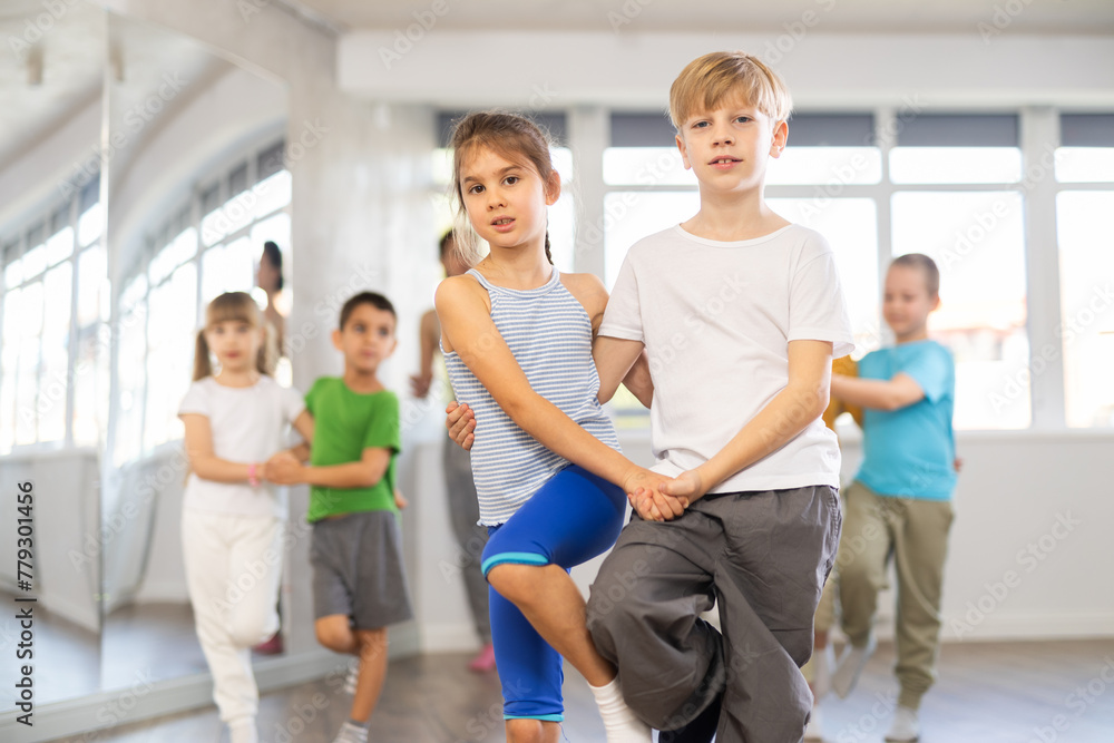 Young children couple learns to quickstep pair dance during dance class in studio, repeat movements and learn slow couple dance. Studio school for amateur and professional dancers