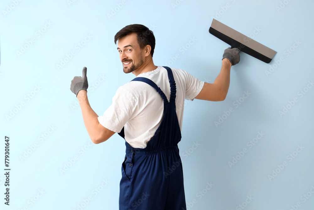 Male decorator with putty knife on blue background Male decorator with putty knife on blue background