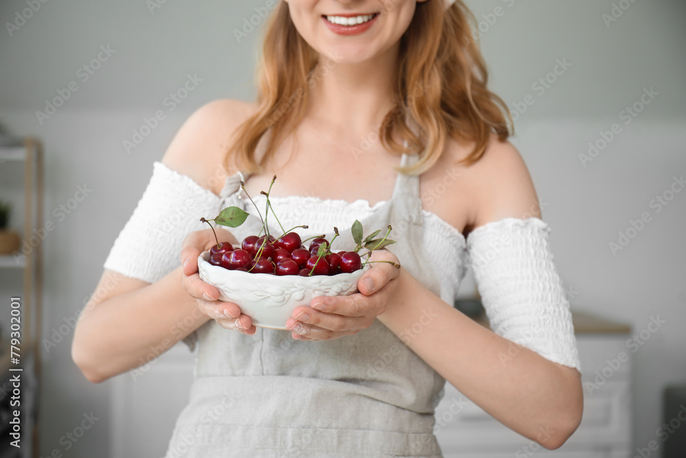 Beautiful happy young woman with bowl of cherries in kitchen Beautiful happy young woman with bowl of cherries in kitchen