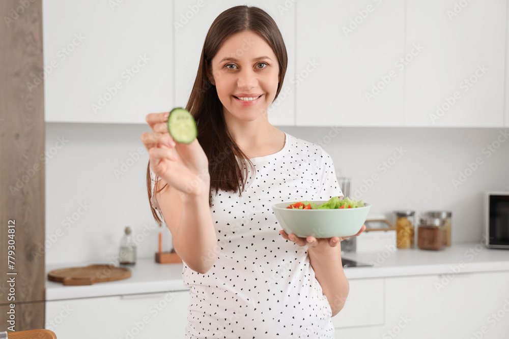 Beautiful pregnant woman eating vegetable salad in kitchen Beautiful pregnant woman eating vegetable salad in kitchen