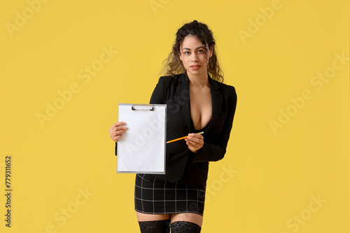 Attractive African-American secretary with clipboard on yellow background photo