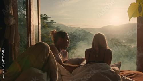 Lovers lying in bed with an amazing view and drinking tea photo