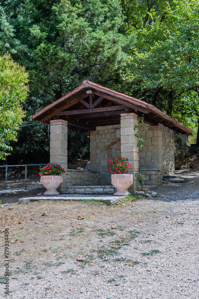 A peaceful park shelter built with stone, under the shade of lush trees in Meteora, Greece A peaceful park shelter built with stone, under the shade of lush trees in Meteora, Greece