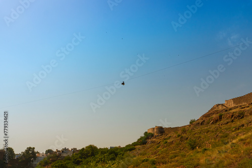 Zipline tourist flying over Rao Jodha Desert Rock Park, Jodhpur, Rajasthan, India. Near the historic Mehrangarh Fort , park contains ecologically restored desert and land vegetation, a tourist spot.