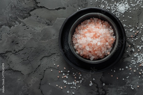 A bowl of pink salt is on a grey surface