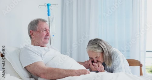 Senior, couple and holding hands in hospital for support, love and kiss with sick husband. Comfort, man and happy woman in clinic for empathy, talk and healthcare for cancer surgery rehabilitation photo