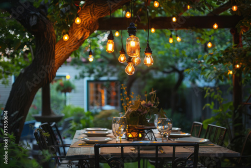 An antique chandelier hangs over an outdoor dining table, casting warm light on the backyard setting. photo