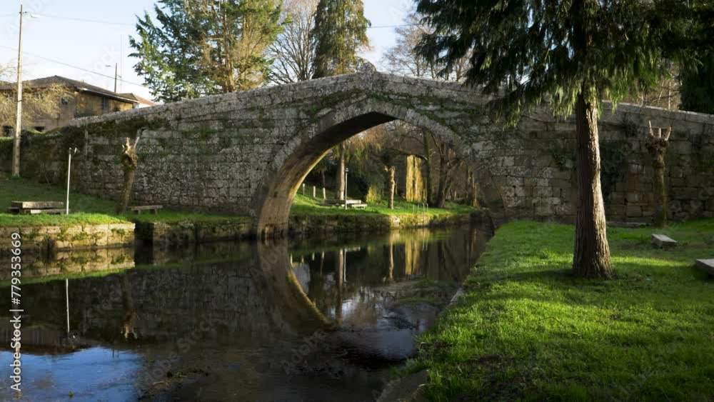 Pan across meditative grassy river banks to Medieval roman bridge in Ourense countryside Pan across meditative grassy river banks to Medieval roman bridge in Ourense countryside