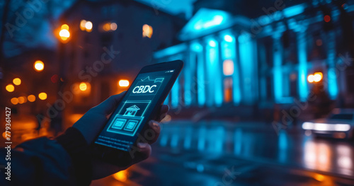 Hand Holding Smartphone Displaying CBDC App Interface with Glowing Building Illustration at Twilight photo
