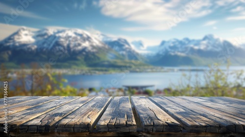 A wooden table is displayed with towering mountains in the blurred background © tashechka