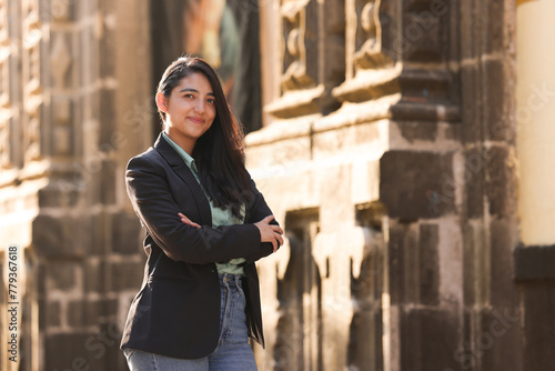 professional mexican woman in formal attire smiling with her arms crossed looking at the camera