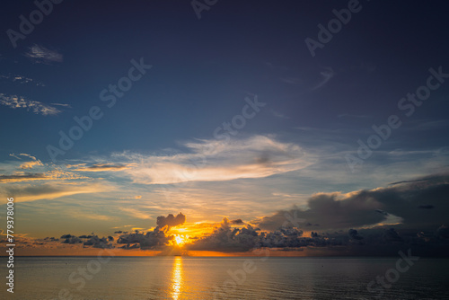 Sunset on tropical beach sea ocean with sunrise clouds. Banner for travel vacation. Scenery sky and reflection rays in water. Beach sunrise over the tropical sea. Tranquil, golden sky background.