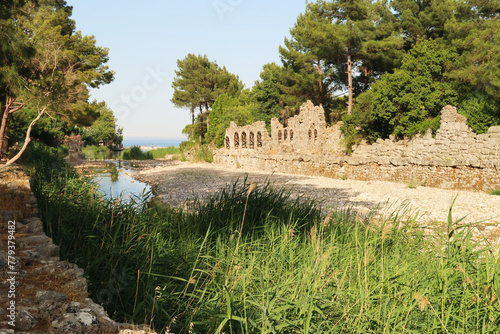 The Göksu river flowing into the Cirali Koyu Bay with the ruins of a bath house next to it at the ancient site of Olympos, Olympus, Turkey