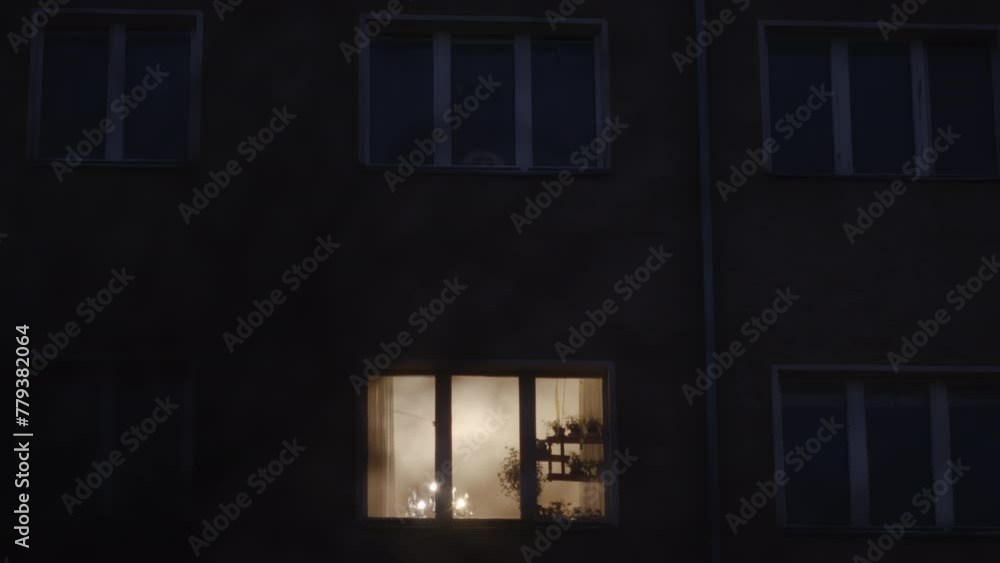 Dark static shot of building with one window showing light from inside. Dark static shot of building with one window showing light from inside.