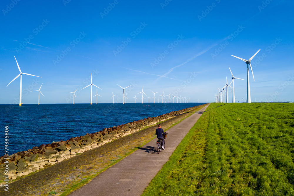 A man riding a electric bike down a path next to a vast wind farm in the Netherlands
