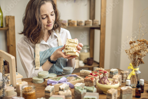 Woman soap maker in a workshop holds pieces of natural soap in her hands. Cozy creative atmosphere and pleasant female hobby