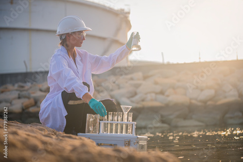Scientist factory wearing protective uniform and glove under working water analysis and water quality by get waste water to check case in laboratory is environment pollution problem concept