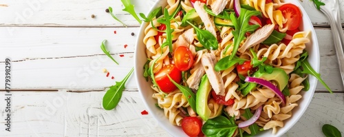 Fresh chicken meat with pasta salad, tomato and basil on white wooden board.