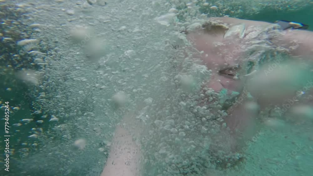 Man submerged underwater, surrounded by bubbles, then surfacing In The Kali Biru (Blue River) Within Tropical Forest in Raja Ampat, West Papua, Indonesia. Man submerged underwater, surrounded by bubbles, then surfacing In The Kali Biru (Blue River) Within Tropical Forest in Raja Ampat, West Papua, Indonesia.