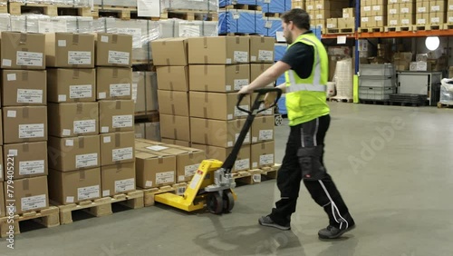 Warehouse interior with stacked boxes on pallets, yellow pallet jack in aisle, fluorescent lighting photo
