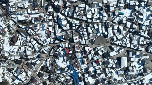 Establishing side tracking top down of Japans Nozawaonsen Mountain Ski Resort Village. Camera hovering above the ski village resort, snow everywhere. Clear Winter Day photo