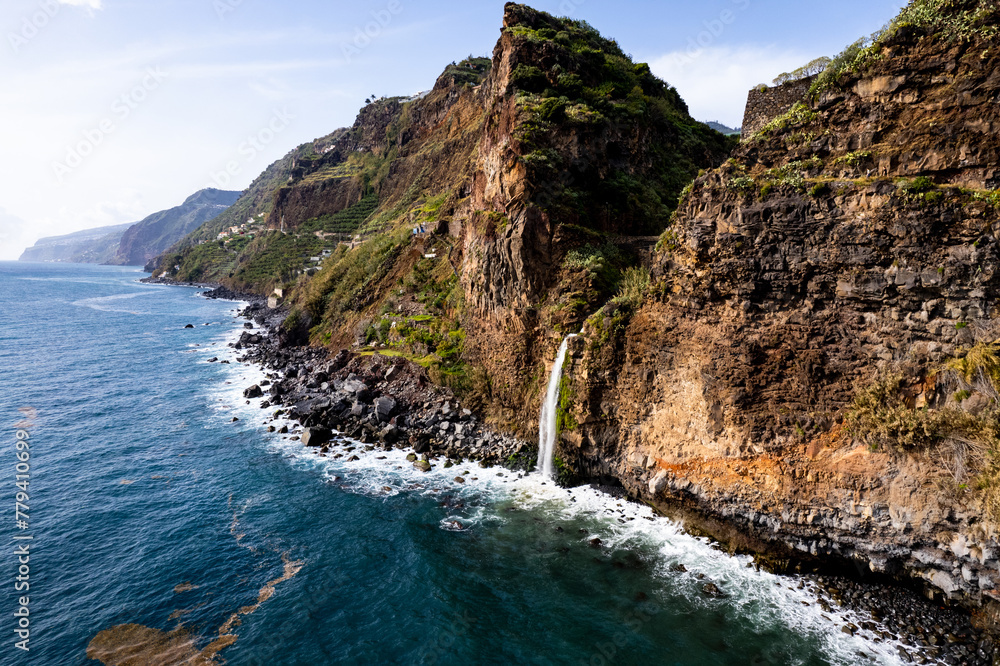Obraz premium Waterfall fall into Atlantic Ocean in Madeira Island, Portugal. Aerial Drone view