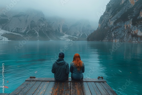 Couple by a mountain lake on a foggy day  pristine waters reflecting nature.