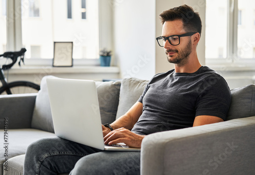 Man working from home sitting on sofa with laptop