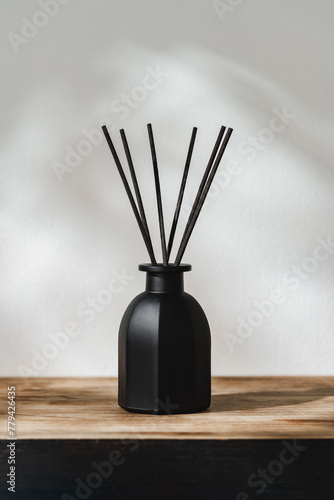Black Reed Diffuser on a Wooden Table With Soft Light Casting Shadows