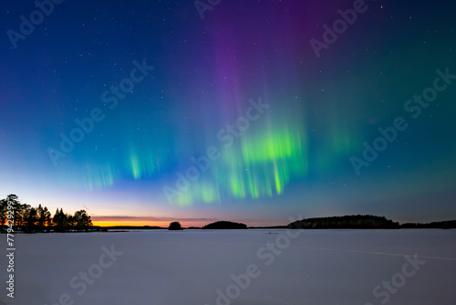 Northern lights dancing over calm lake in north of Sweden