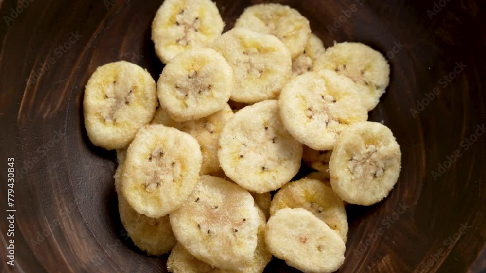 Dried organic bananas in wooden brown bowl top view. Crunchy dry fruit chips close up. Rotation Dried organic bananas in wooden brown bowl top view. Crunchy dry fruit chips close up. Rotation