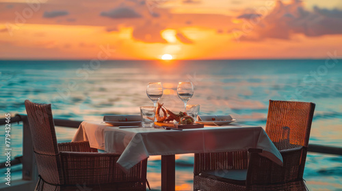 Romantic dinner setting on the beach at sunset. Romantic dinner at the beach restaurant overlooking the sunset on the ocean on a beautifully served table with seafood and white wine.