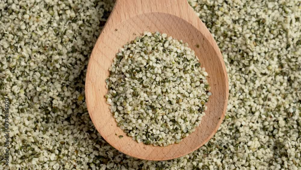 Hemp seeds in rustic wooden spoon close up. Peeled nutritious Cannabis sativa grains. Superfood ingredient. Rotation