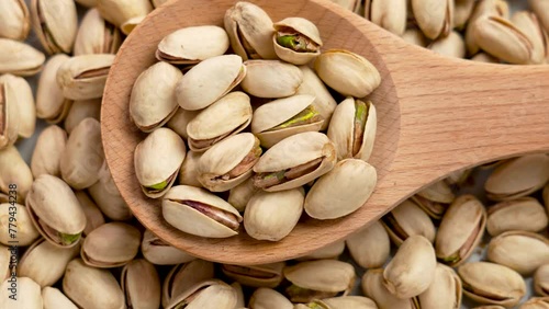 Roasted nutritious pistachio nuts in a wooden kitchen spoon close up. Health food ingredients. Rotation