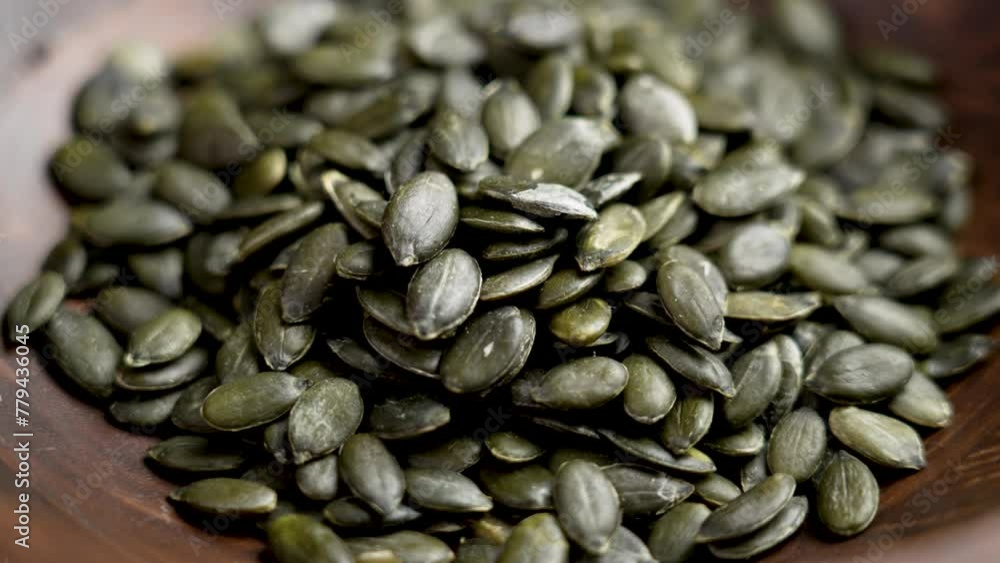Wooden bowl of green peeled pumpkin seeds close up. Healthy food. Rotation Wooden bowl of green peeled pumpkin seeds close up. Healthy food. Rotation