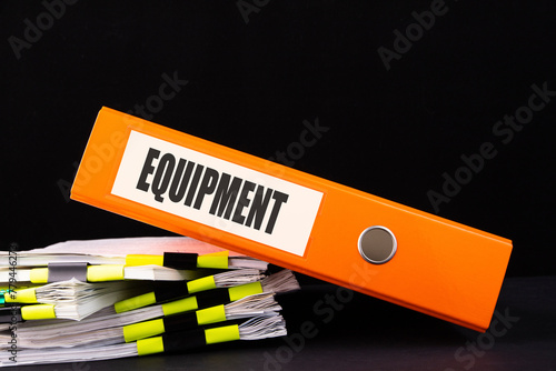 EQUIPMENT word on folder on a black background with documents. Business and finance concept. photo