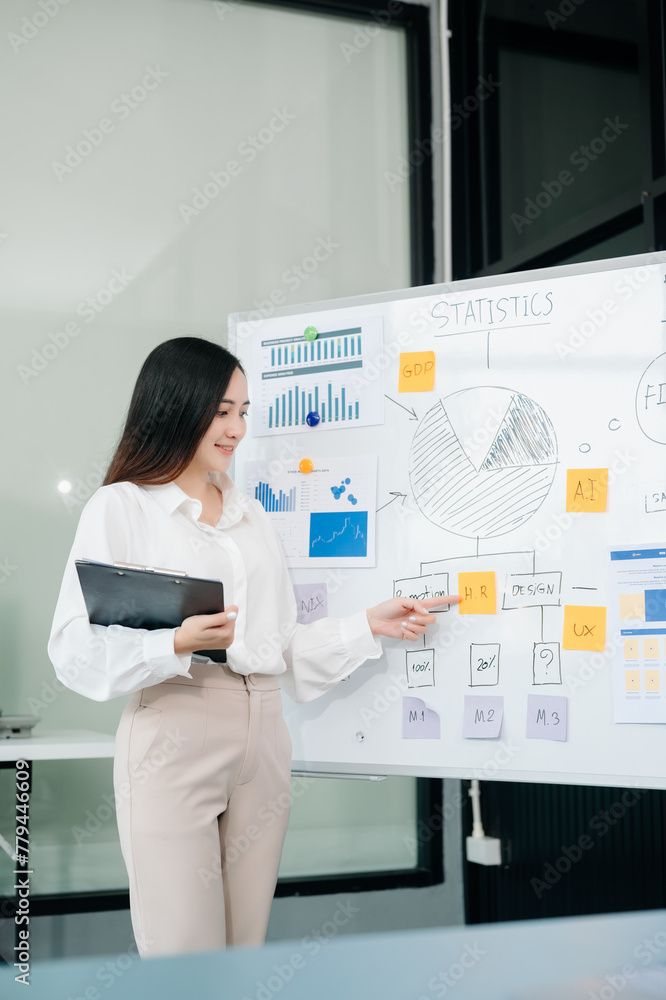 Asian businesswoman holding a pen taking note on note-paper attached to a mirror as a reminder laptop and tablet on the desk. Asian businesswoman holding a pen taking note on note-paper attached to a mirror as a reminder laptop and tablet on the desk.